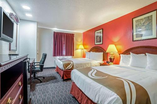 a hotel room with two beds and a flat screen tv at Quality Inn South in Wichita