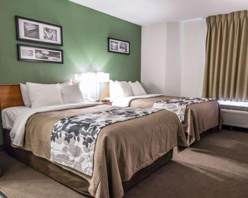 2 letti in una camera d'albergo con pareti verdi di Sleep Inn a Louisville