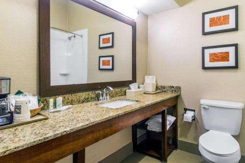a bathroom with a toilet and a sink and a mirror at Quality Suites in Corbin