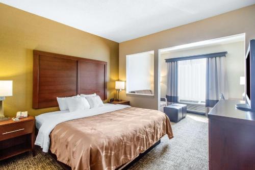 a hotel room with a bed and a television at Quality Suites in Corbin