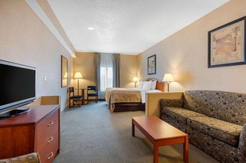 a hotel room with a couch and a bed and a television at Quality Inn & Suites Benton - Draffenville in Draffenville