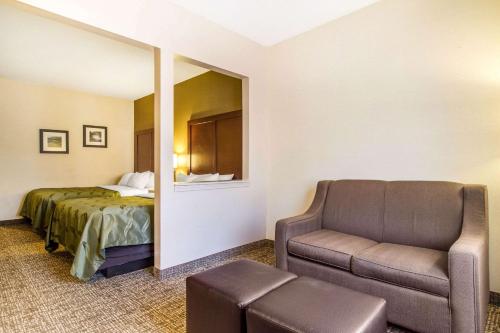 a hotel room with a bed and a couch and a chair at Quality Suites in Corbin