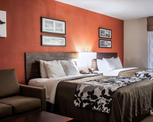 a hotel room with two beds and a chair at Sleep Inn & Suites Fort Campbell in Oak Grove