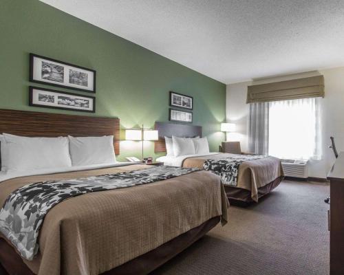 a hotel room with two beds and a window at Sleep Inn & Suites Middlesboro in Middlesboro