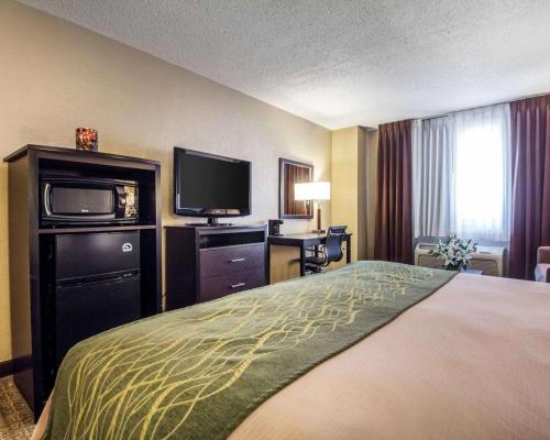 a hotel room with a bed and a flat screen tv at Quality Inn Harlan in Harlan