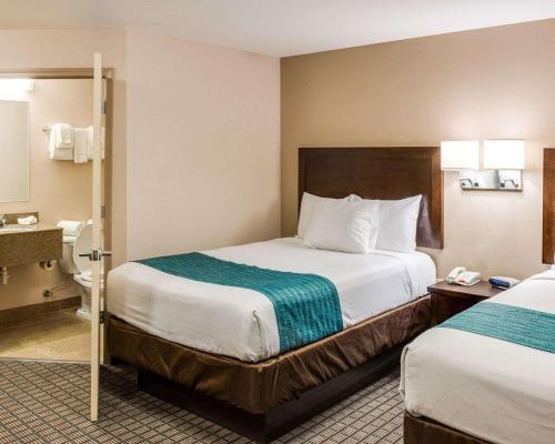 a hotel room with two beds and a bathroom at Suburban Studios Avondale in Avondale