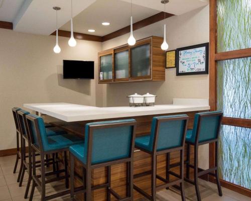 a kitchen with a bar with chairs around it at Comfort Suites Bossier City - Shreveport East in Bossier City