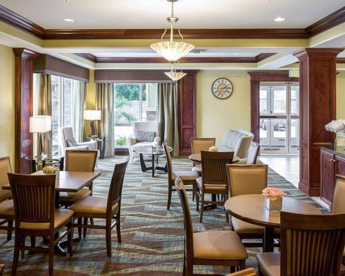 a restaurant with tables and chairs and a living room at Comfort Suites Harvey - New Orleans West in Harvey