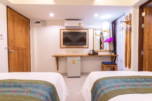 a room with two beds and a tv on the wall at Anumat Premium Budget Hotel in Chiang Mai