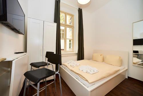 a small bedroom with a bed and two chairs at Bearlin City Apartments - City Center East in Berlin