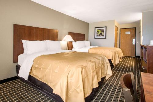 a hotel room with two beds and a chair at Quality Inn Madison West Near University Area in Madison