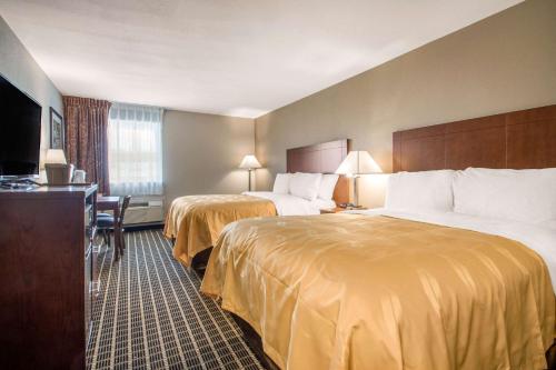 a hotel room with two beds and a flat screen tv at Quality Inn Madison West Near University Area in Madison