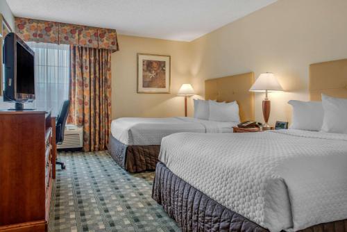 a hotel room with two beds and a flat screen tv at Quality Hotel Conference Center Cincinnati Blue Ash in Blue Ash