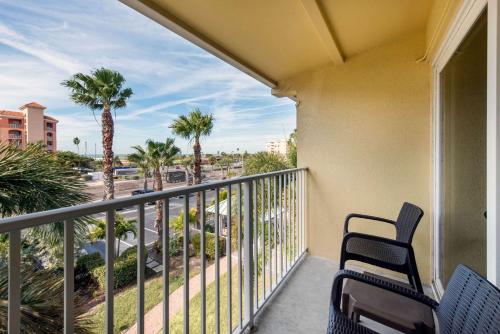 a balcony with two chairs and palm trees at Treasure Island Hotel and Marina in St Pete Beach