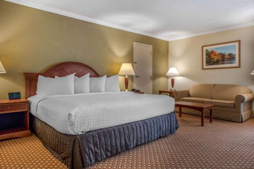 Habitación de hotel con cama grande y sofá en Quality Hotel Conference Center Cincinnati Blue Ash en Blue Ash