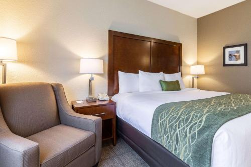 a hotel room with a bed and a chair at Comfort Inn South Tulsa - Woodland Hills in Tulsa