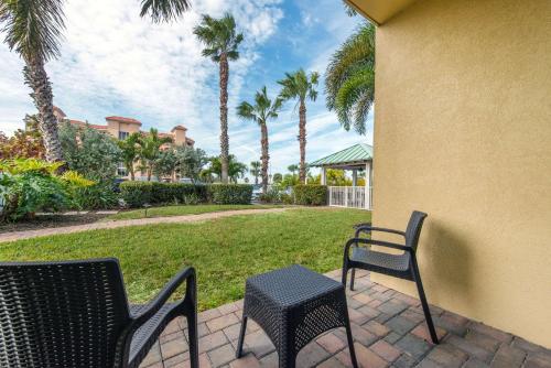 two chairs and a table on a patio with palm trees at Treasure Island Hotel and Marina in St Pete Beach