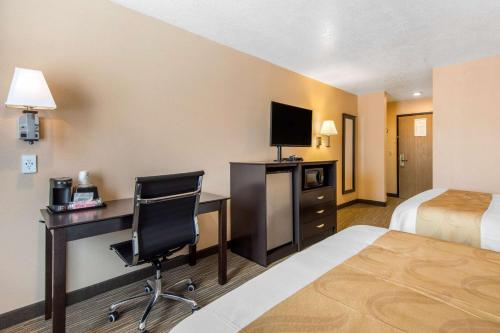 a hotel room with a desk with a computer and a bed at Quality Inn & Suites Albuquerque North near Balloon Fiesta Park in Albuquerque
