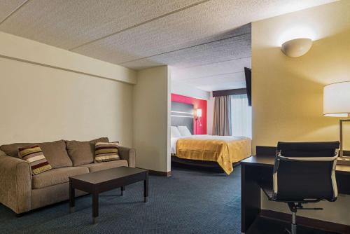 a hotel room with a couch and a bed at Quality Suites Atlanta Airport East in Forest Park