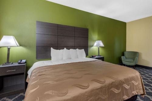 a hotel room with a large bed and a chair at Quality Inn in Kingstree