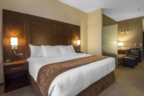 a hotel room with a large bed and a chair at Comfort Suites in Saskatoon