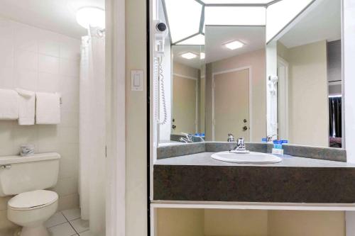 a bathroom with a sink and a toilet and a mirror at Travelodge by Wyndham Trois-Rivieres in Trois-Rivières
