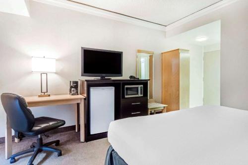 a room with a bed and a desk with a television at Travelodge by Wyndham Trois-Rivieres in Trois-Rivières
