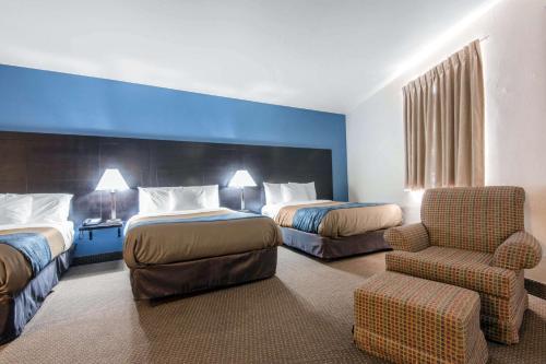 um quarto de hotel com duas camas e uma cadeira em Econo Lodge Sudbury em Sudbury