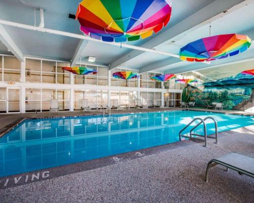 Clarion Inn and Events Center Pueblo North في بويبلو: حمام سباحة مع مظلات ملونة فوقه