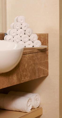 a bowl of toilet paper on a shelf with towels at Al Khoory Executive Hotel, Al Wasl in Dubai