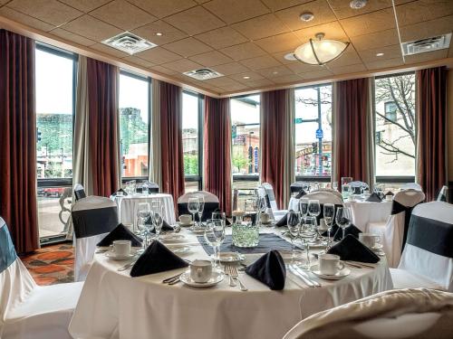 un restaurante con mesas y sillas blancas y ventanas en The Golden Hotel, Ascend Hotel Collection en Golden