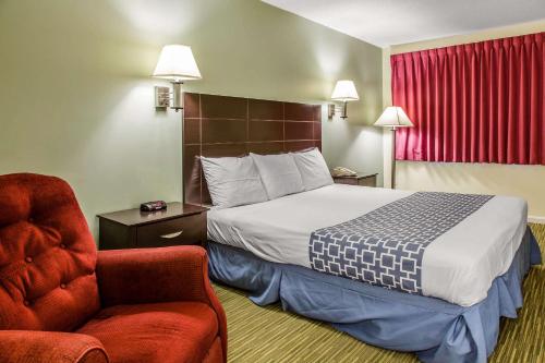 a hotel room with a bed and a chair at Rodeway Inn in Groton