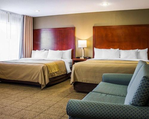 a hotel room with two beds and a chair at Comfort Inn Guilford near I-95 in Guilford