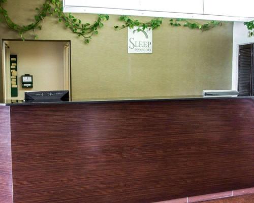 a wooden reception counter with a sign on the wall at Sleep Inn & Suites Niantic North in Niantic