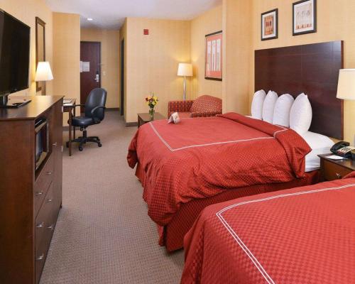 a hotel room with two beds and a flat screen tv at Quality Suites Stratford in Stratford