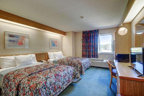 a hotel room with two beds and a desk at Rodeway Inn Willington North in Willington Hill