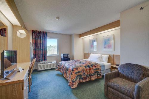 Willington HillにあるRodeway Inn Willington Northのベッドと椅子のあるホテルの部屋