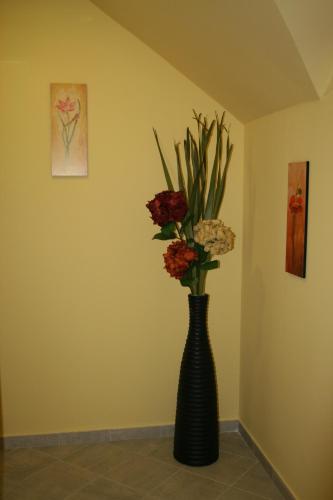 a black vase with flowers in a room at Panoráma Panzió in Matrafured