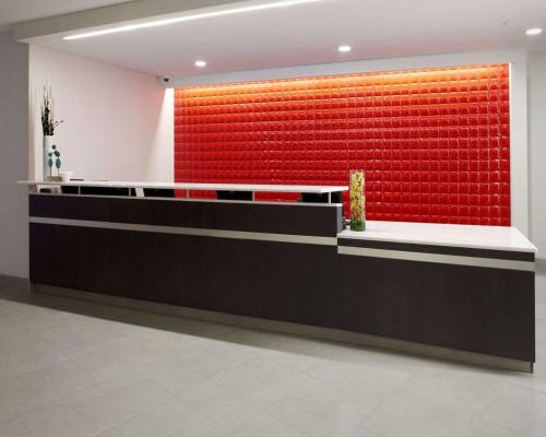 a reception desk with a red wall in a lobby at Cambria Hotel Washington, DC Convention Center in Washington, D.C.