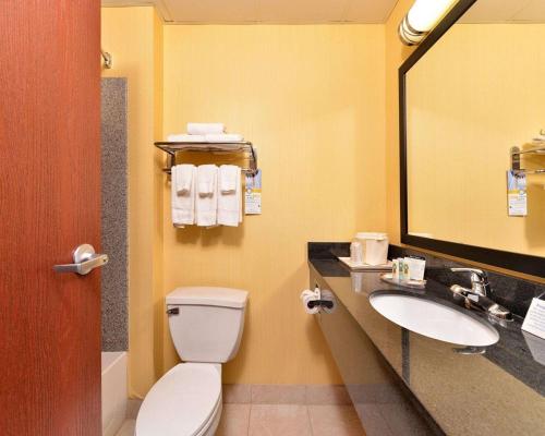 a bathroom with a toilet and a sink and a mirror at Quality Suites Stratford in Stratford