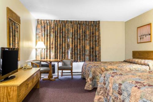 a hotel room with two beds and a desk and a television at Rodeway Inn Waterford - New London in Waterford