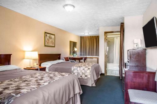 a hotel room with two beds and a television at Rodeway Inn & Suites Branford - Guilford in Branford