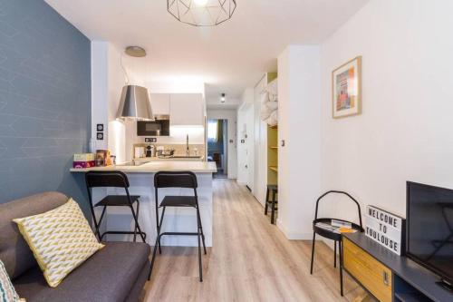 un salon avec un canapé et une cuisine avec un comptoir dans l'établissement Calme appart rénové Jardin des Plantes Busca, à Toulouse