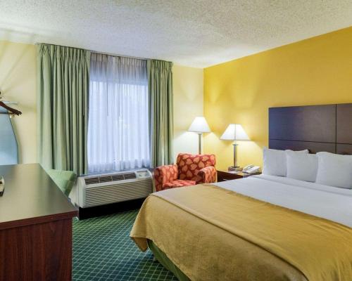Quality Inn في نيوارك: غرفه فندقيه بسرير وكرسي