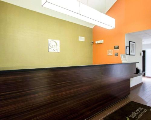 an office lobby with orange and green walls and wood floors at Sleep Inn Ormond Beach - Daytona in Ormond Beach