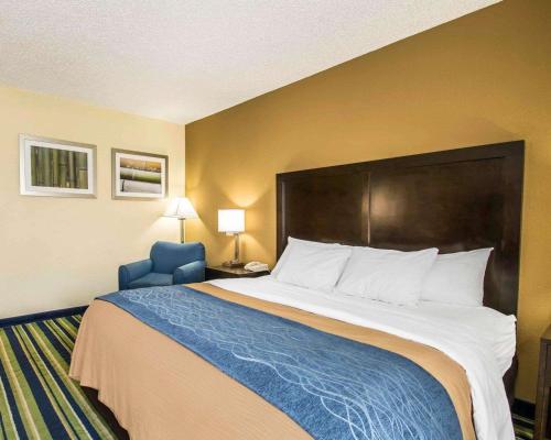 a hotel room with a large bed and a blue chair at Comfort Inn & Suites Lantana - West Palm Beach South in Lantana