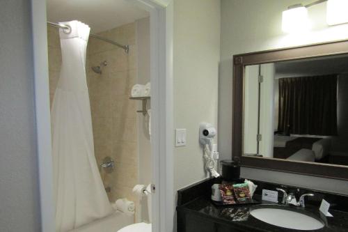 a bathroom with a sink and a shower with a mirror at Quality Inn & Suites Kissimmee by The Lake in Orlando