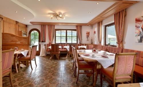 a dining room with tables and chairs and windows at Ticklhof am See in Thiersee