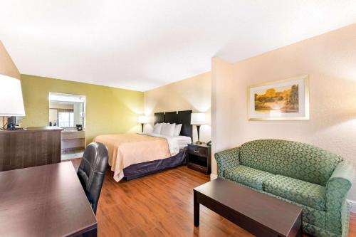 オーランドにあるQuality Inn & Suites Orlando Airportのベッド、ソファ、テーブルが備わるホテルルームです。
