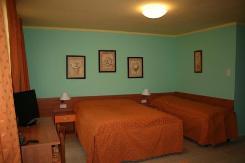 a hotel room with two beds and a television at Panoráma Panzió in Matrafured